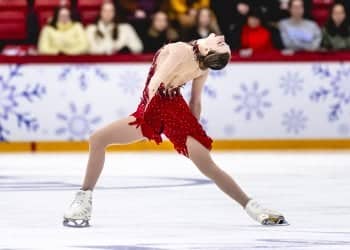 Dressed in all red, Sarah Everhardt leans back as she glides across the ice.