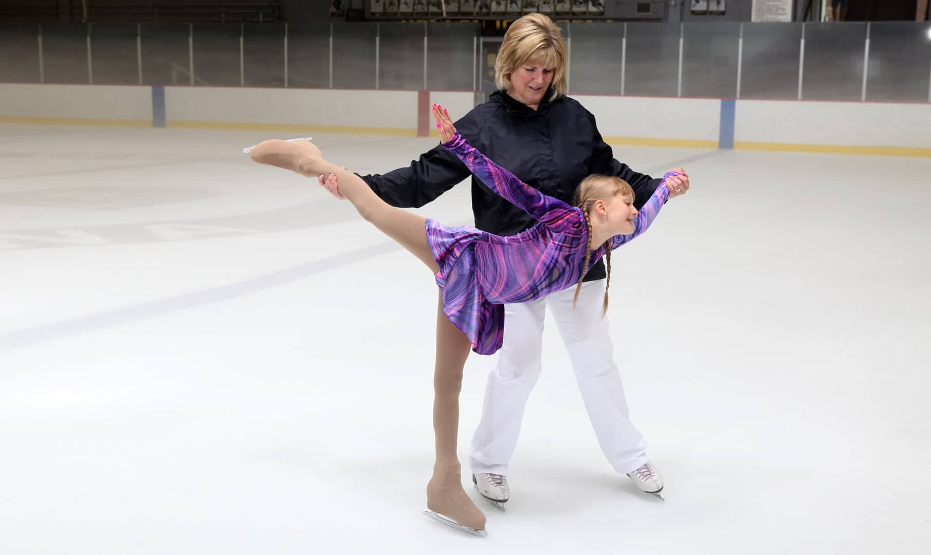 A coach helps a young skater.